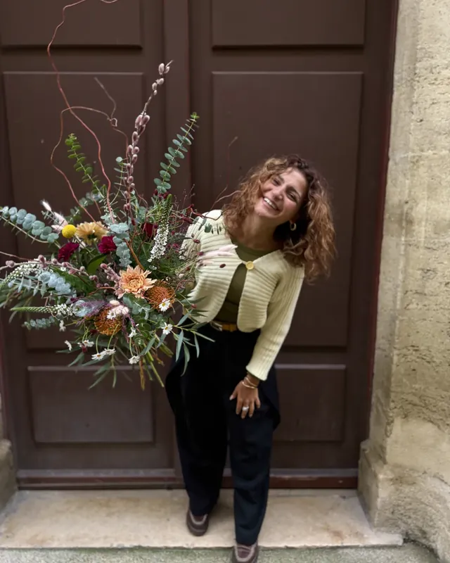 The florist holding a country-style bouquet in front of a wooden door
